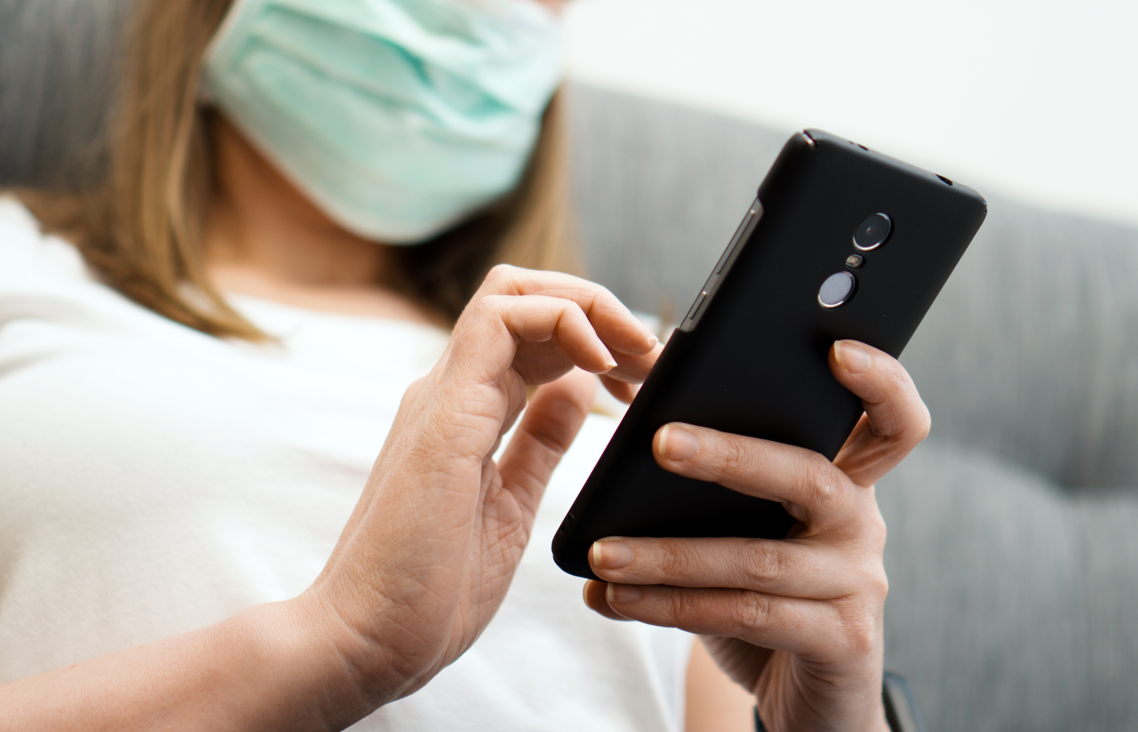 Stock image of woman in health face mask using smart phone